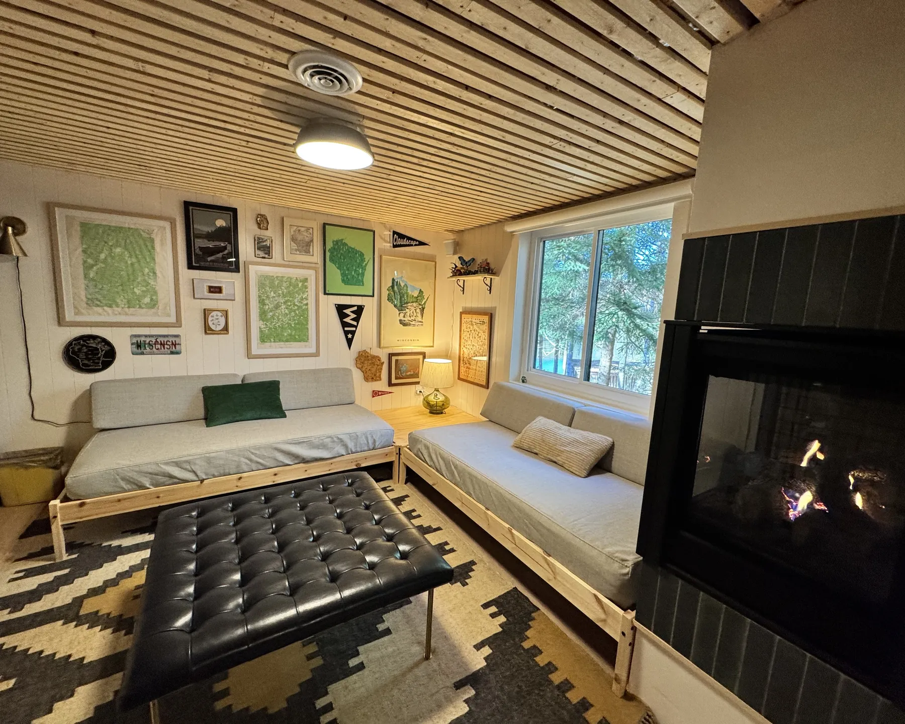 Lower level corner after the remodel, slatted wood ceiling and daybeds with a gallery wall