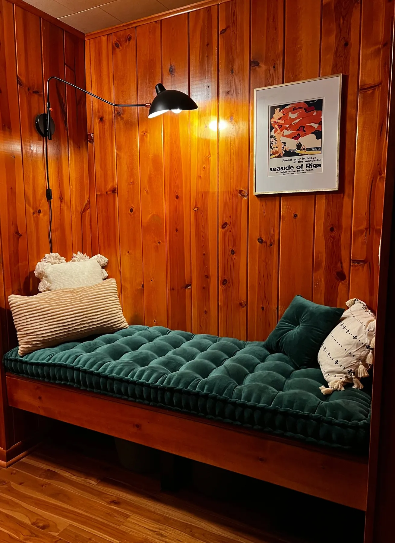 Built-in wood bench with a green velvet cushion and a black swing arm sconce
