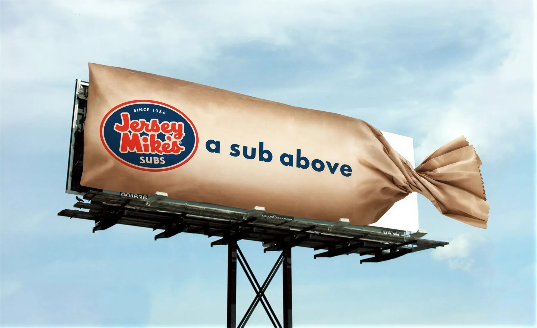 Billboard of a giant Jersey Mike's sub wrapped in its paper bag, reading a sub above