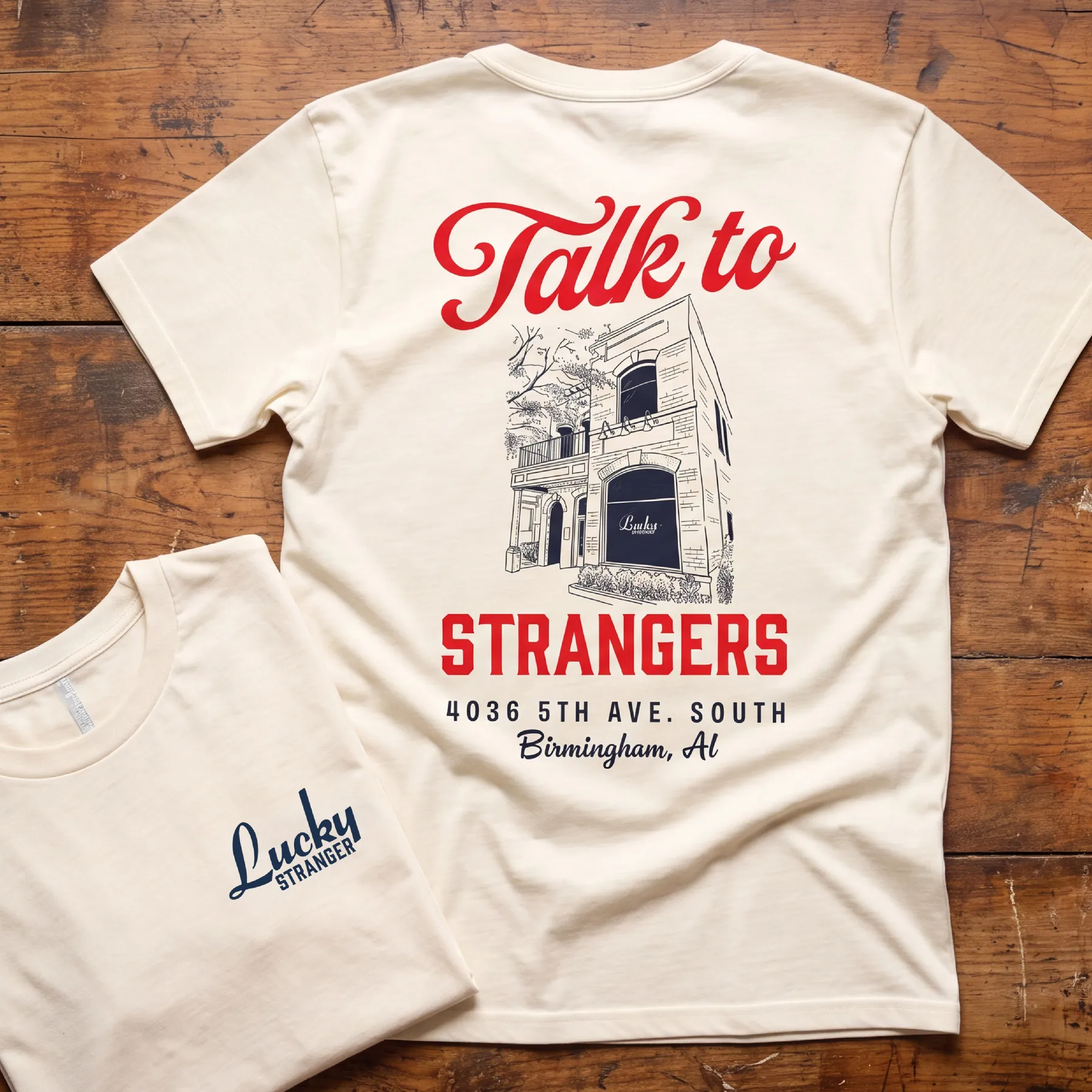 Lucky Stranger T-shirt with illustrated bar facade on a wood table